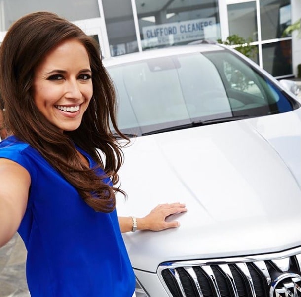 Picture of Kaylee Hartung posing for a photoshoot with her car wearing blue color dress